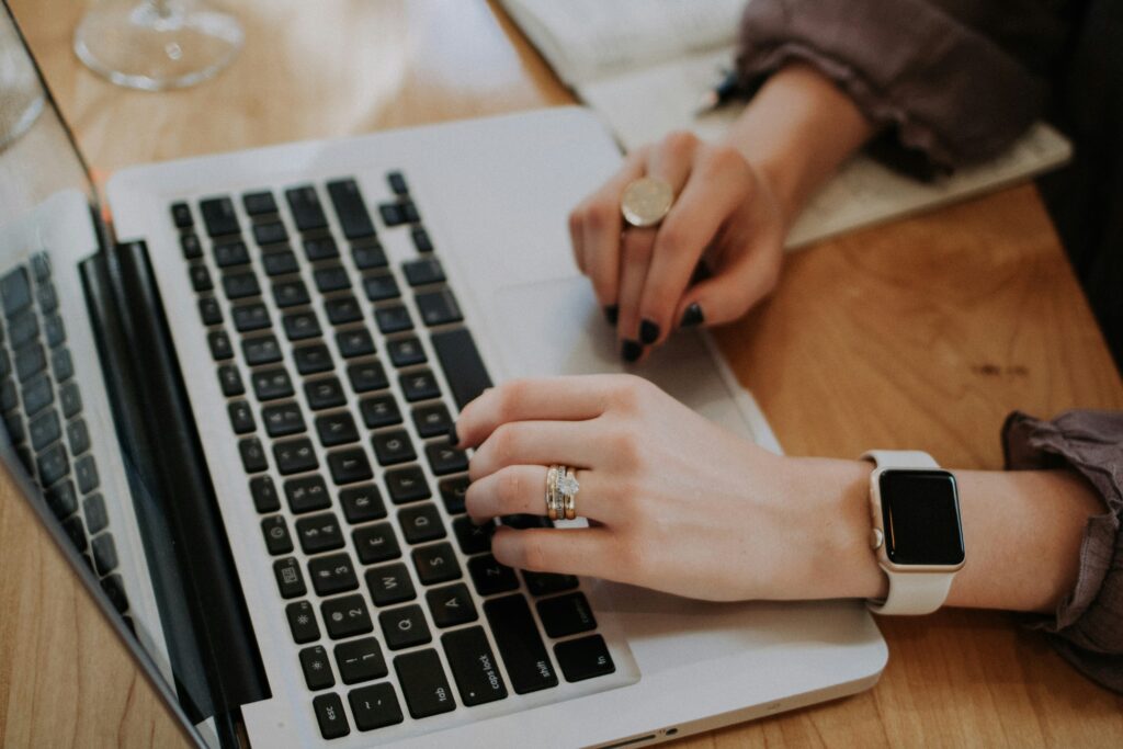 Frauen Hände mit Ringen auf an einem Laptop tippend