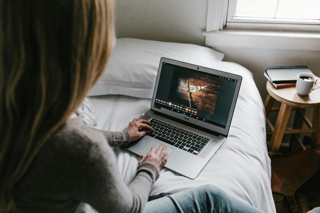 Eine Frau, sitzend auf einem Bett mit einem Laptop